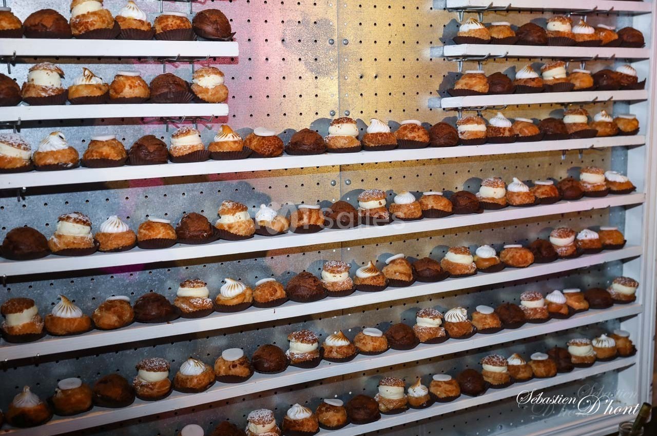 Étagères remplies de choux pâtissiers variés, alignés en rangées sur un fond perforé métallique.