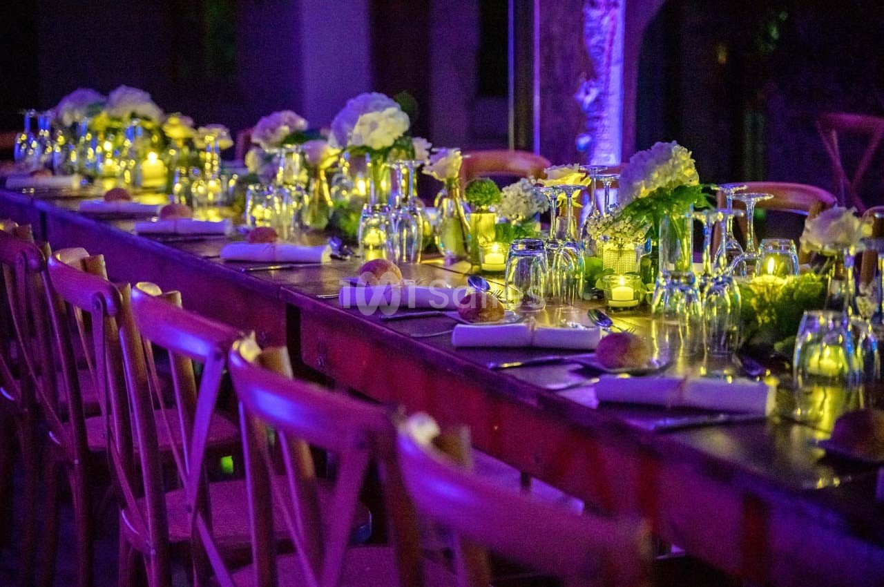 Table décorée avec des fleurs, bougies et vaisselle élégante, éclairée par une lumière tamisée dans une ambiance festive.