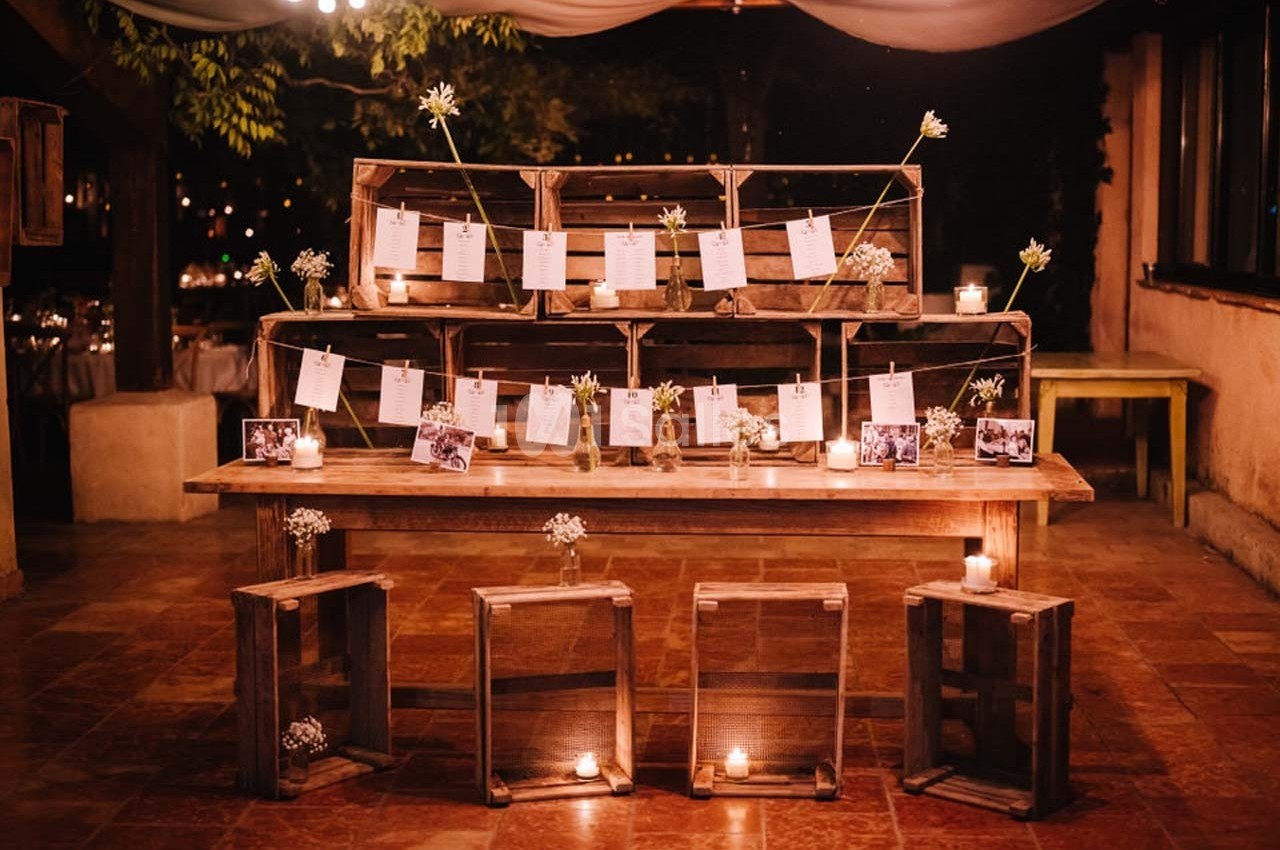Décoration de mariage avec des caisses en bois, photos et bougies disposées sur une table dans une ambiance chaleureuse.