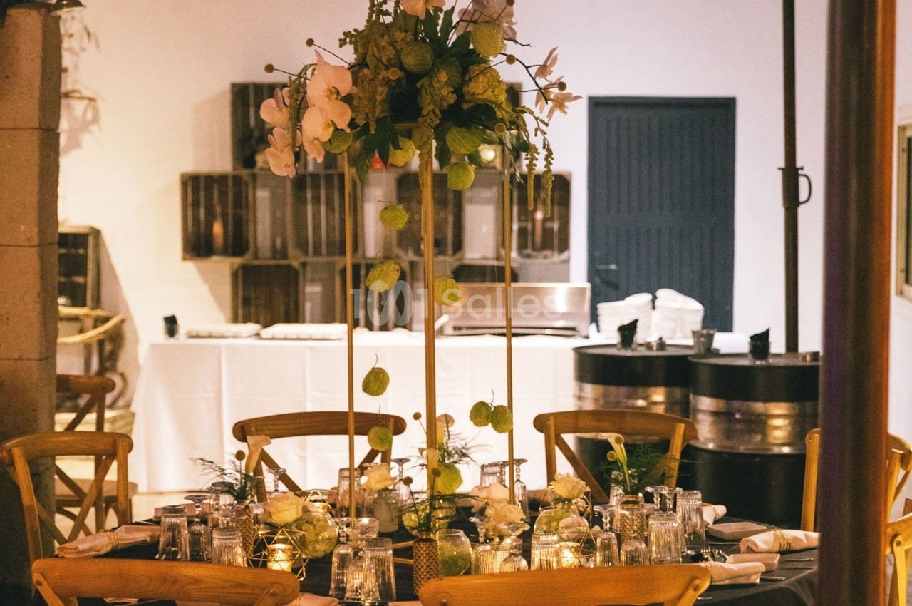 Table élégamment dressée avec un centre de table floral, entourée de chaises en bois dans une salle de réception.