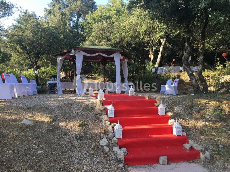 Escalier extérieur recouvert d'un tapis rouge menant à une pergola décorée pour un événement en plein air.