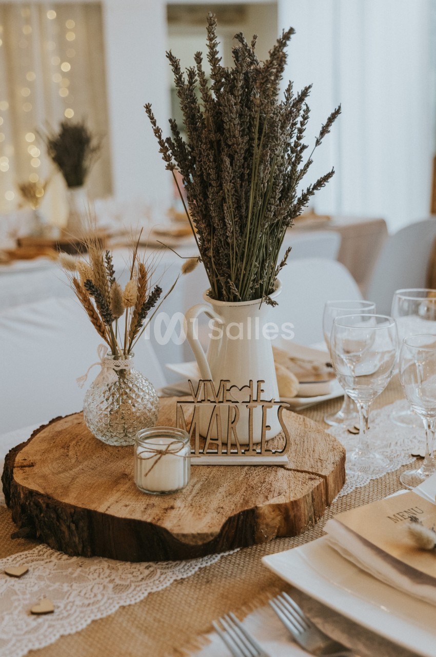 Centre de table rustique avec rondin de bois, bouquet de lavande, bougie et décoration ’Vive les mariés’.
