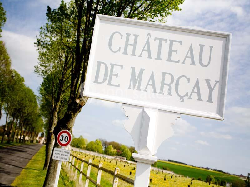 Panneau indiquant ’Château de Marçay’ au bord d'une route bordée d'arbres et de champs verdoyants.