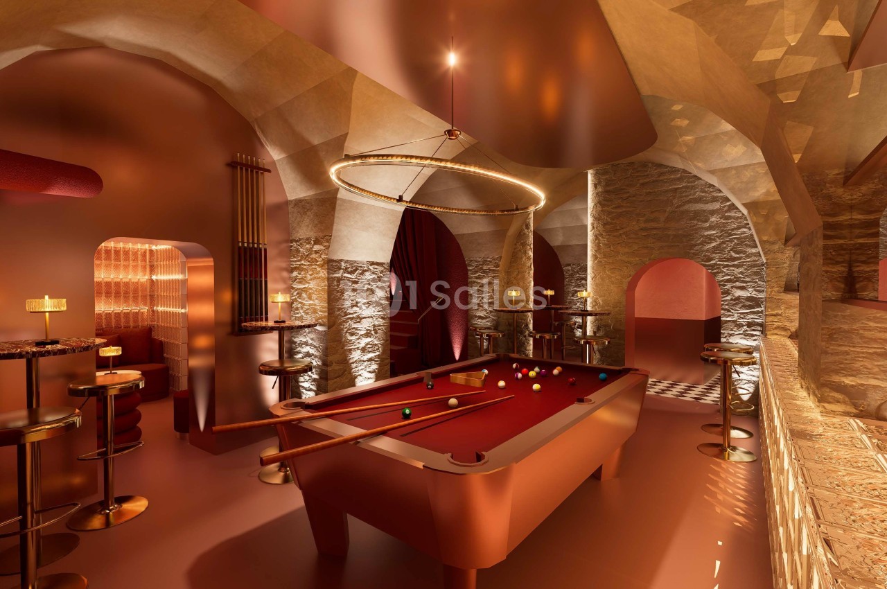 Salle de billard élégante avec éclairage tamisé, murs en pierre, table de billard rouge et mobilier moderne.