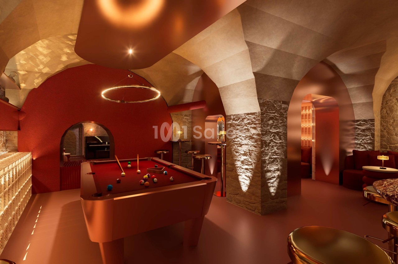 Salle voûtée au décor chaleureux avec billard rouge au centre, éclairage tamisé et mobilier élégant.