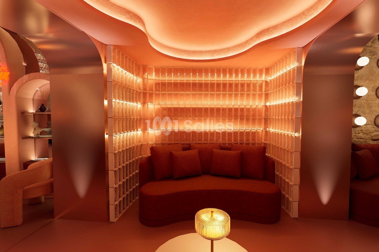 Espace lounge avec banquette incurvée, éclairage tamisé et murs texturés dans des tons chauds.