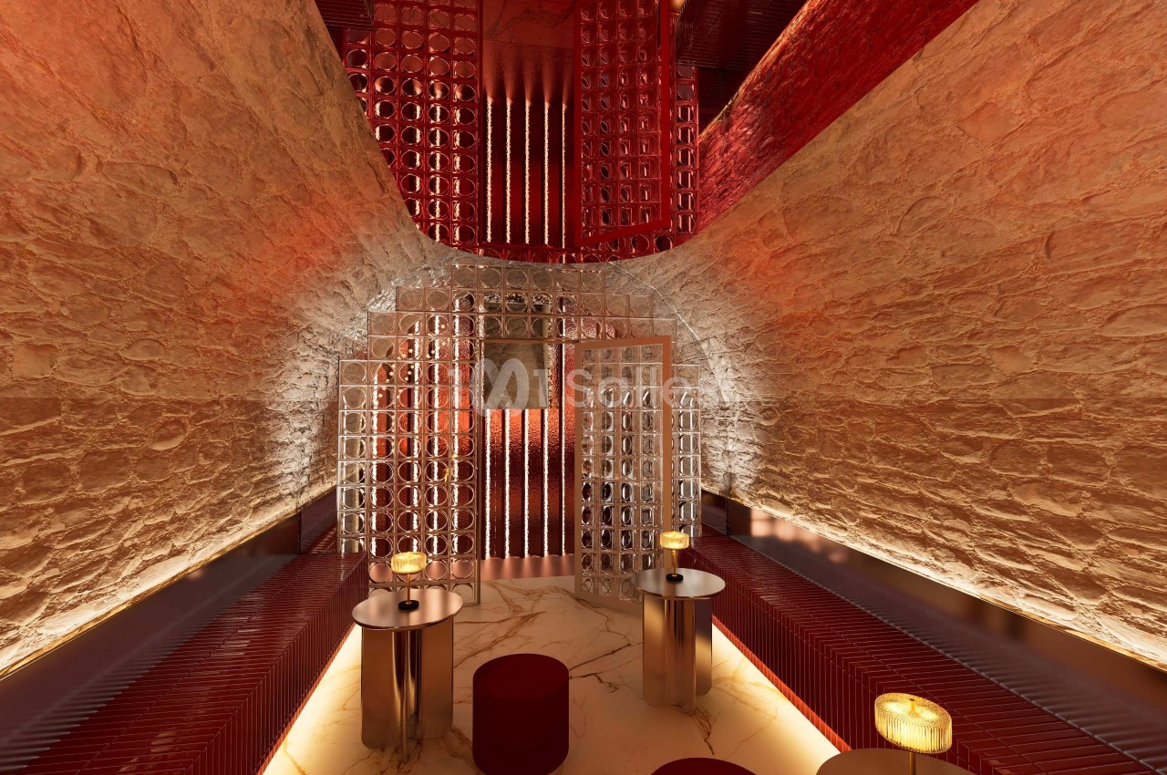 Salle voûtée en pierre avec éclairage tamisé, mobilier moderne et tables rondes éclairées par des bougies.