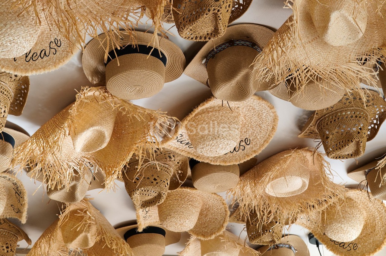 Chapeaux en paille suspendus au plafond, variés par leurs formes, motifs et ornements.