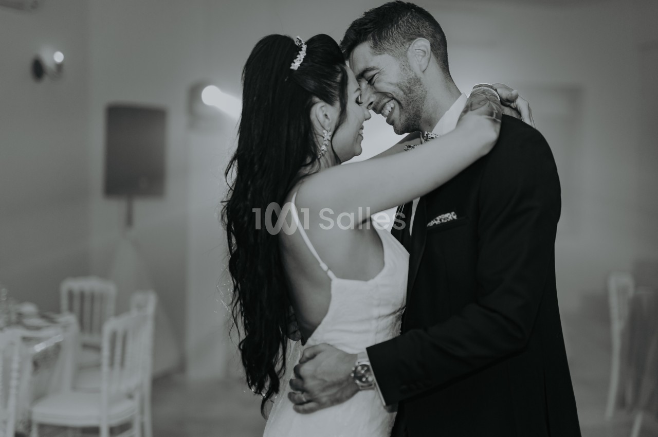 Un couple en tenue de mariage danse ensemble dans une salle éclairée de manière douce.