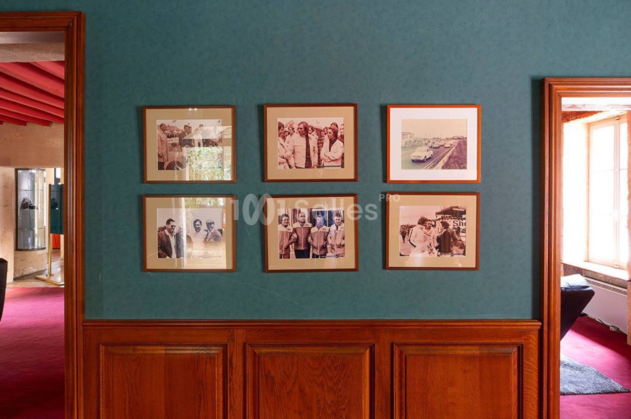 Mur décoré de six cadres photo alignés, dans une pièce aux murs bleus et boiseries en bas.