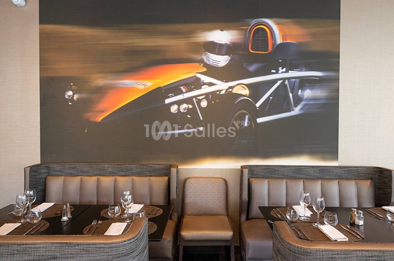 Photo d'un restaurant avec des banquettes et une grande fresque murale représentant une voiture de sport en mouvement.