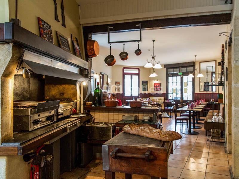 Cuisine ouverte d'un restaurant rustique avec un four, un plan de travail en bois et une salle de restauration en arrière…