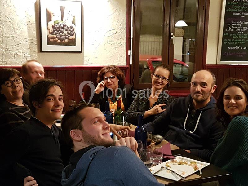 Un groupe de personnes assises autour d'une table dans un restaurant, souriant et discutant.