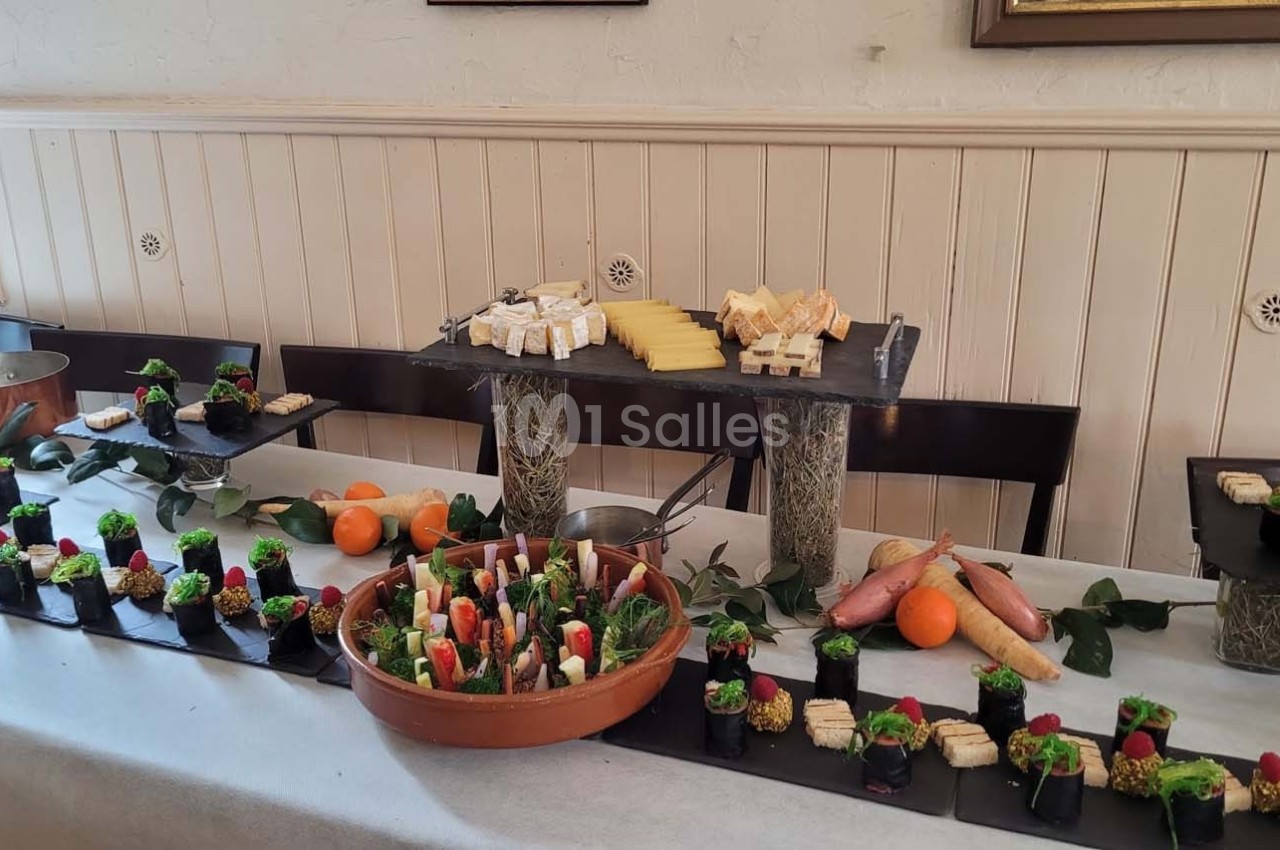 Buffet composé de fromages, légumes, et amuse-bouches variés disposés sur une table décorée.