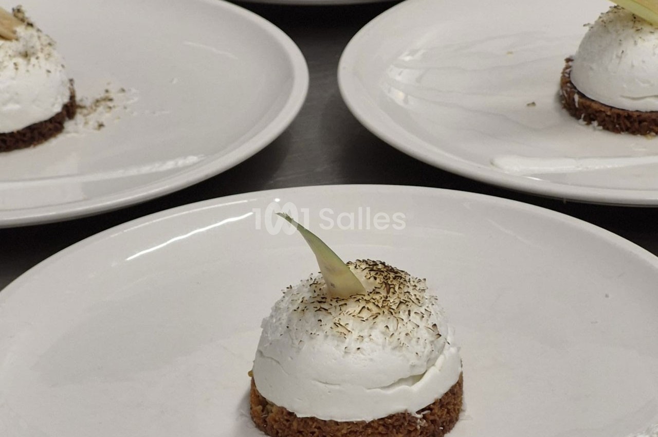 Dessert individuel composé d'une base croustillante, d'une mousse blanche et d'une décoration fine sur le dessus.