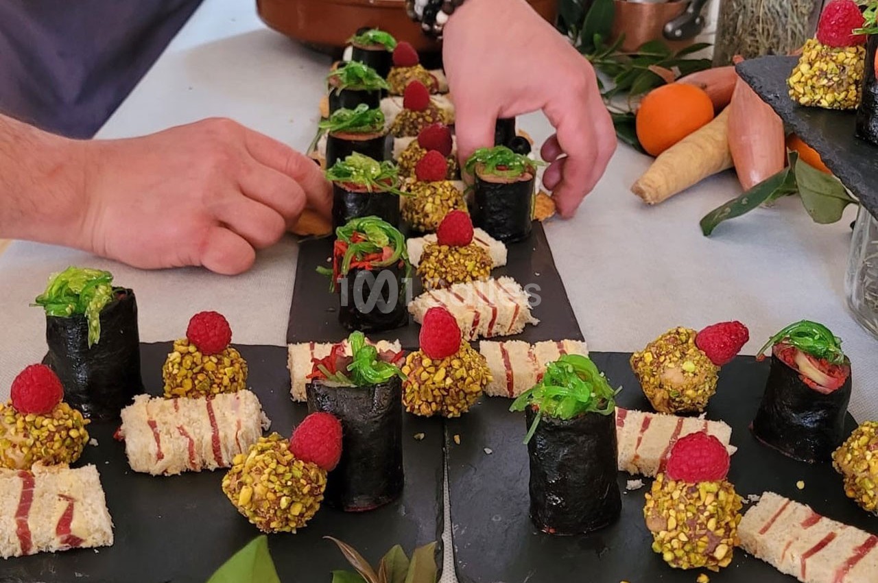 Assiette garnie de bouchées variées : makis, tranches de pain garnies et boulettes enrobées de pistaches.
