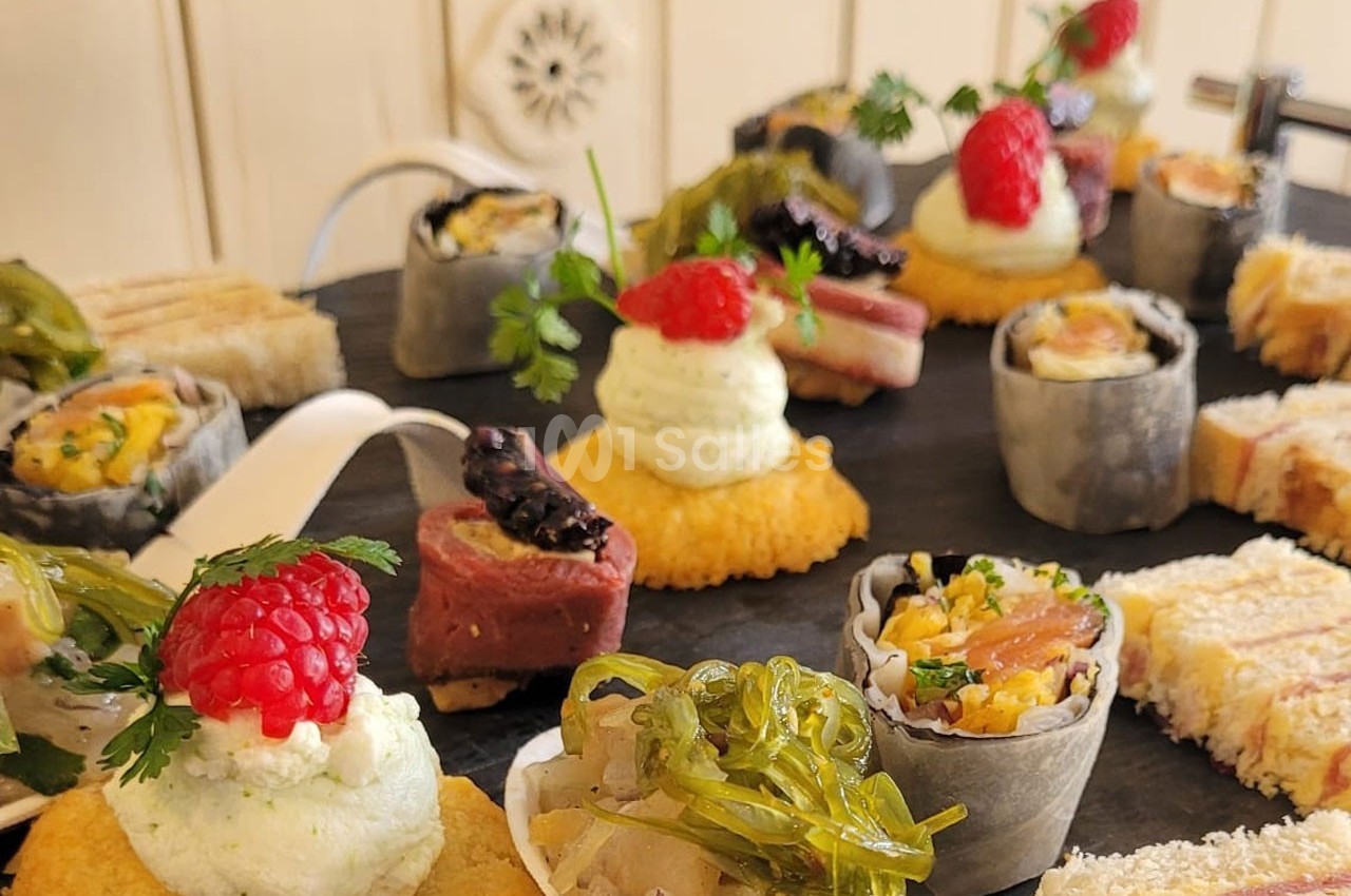 Assortiment de bouchées apéritives variées sur un plateau, incluant fruits, légumes, et garnitures raffinées.