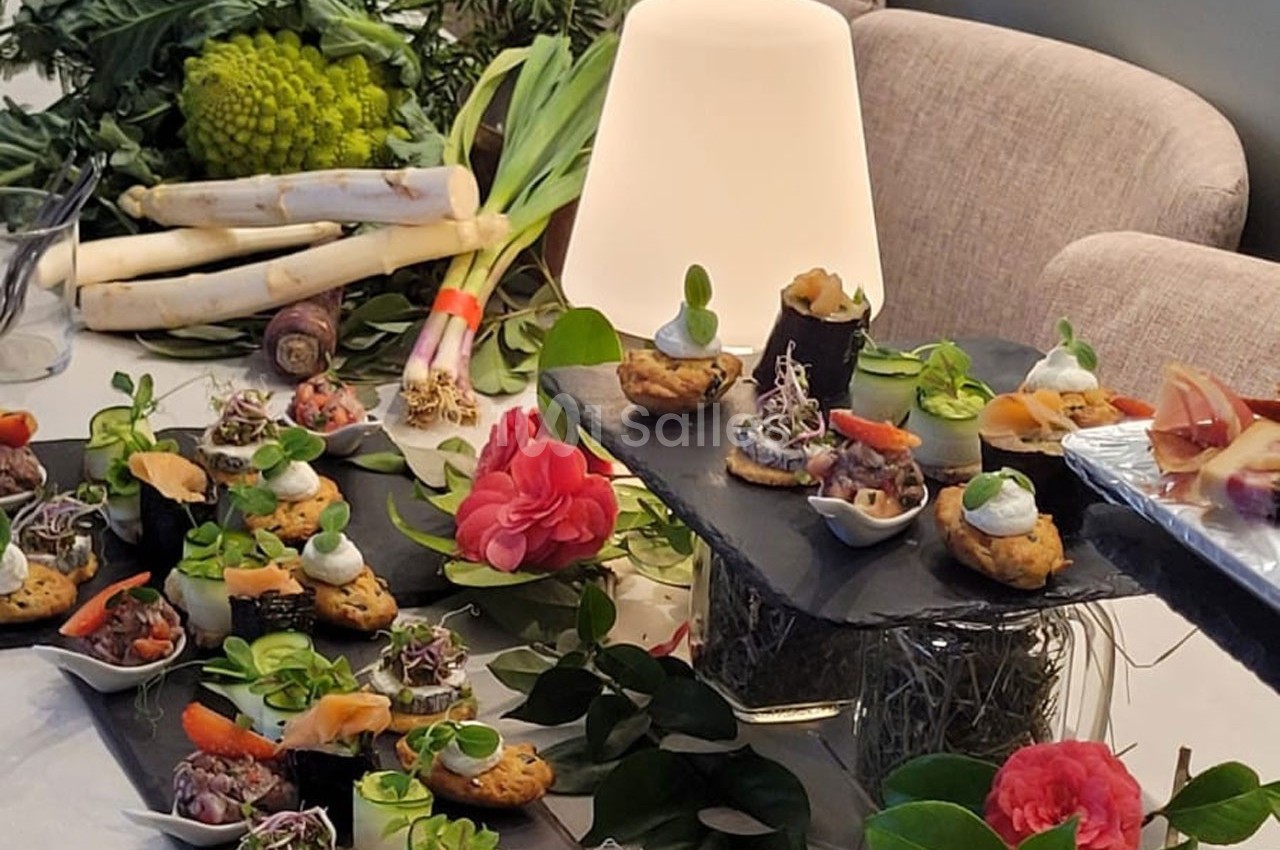 Plateau de bouchées apéritives variées avec légumes frais en arrière-plan et décoration florale.