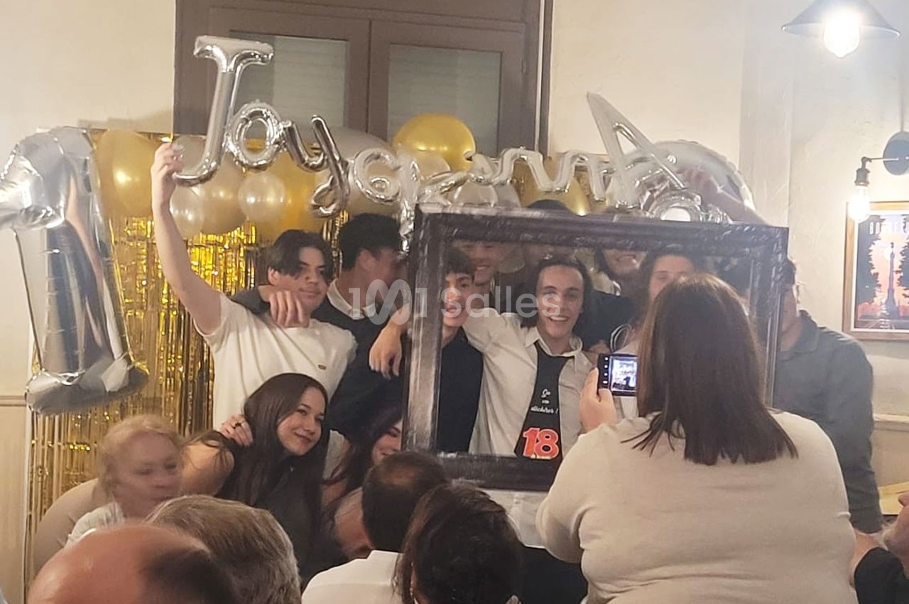 Un groupe de jeunes pose avec un cadre photo devant des ballons et une décoration festive lors d'une célébration.