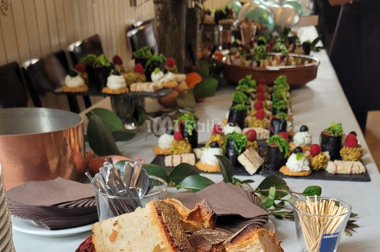 Buffet avec pain, desserts variés, verrines et décorations végétales sur une table dressée pour un événement.