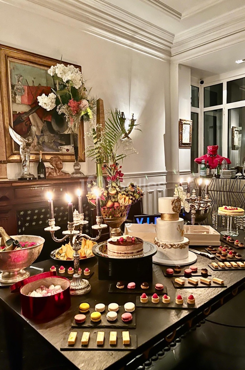 Table élégamment dressée avec des desserts variés, bougies allumées et décorations florales dans un intérieur raffiné.