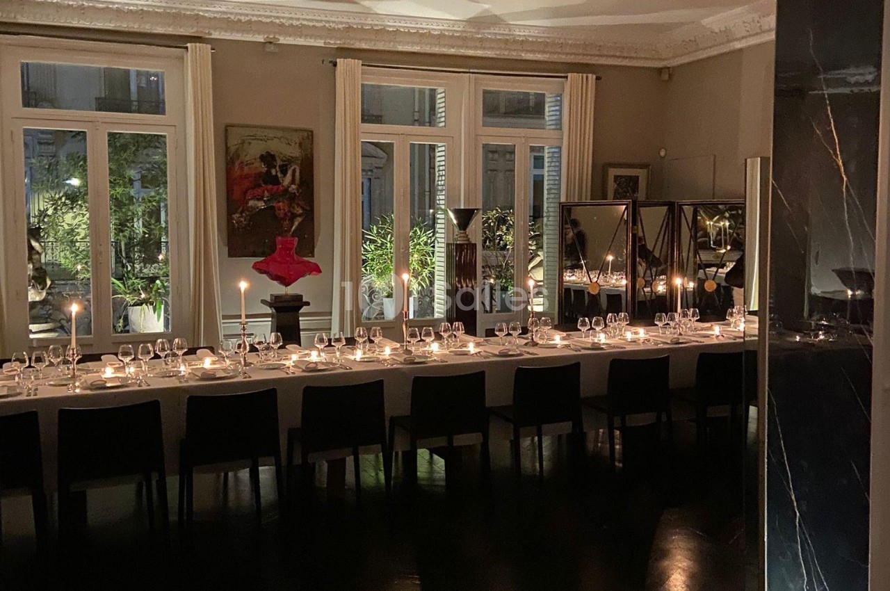Grande table élégamment dressée dans une salle à manger avec bougies allumées, baignée par une lumière tamisée.