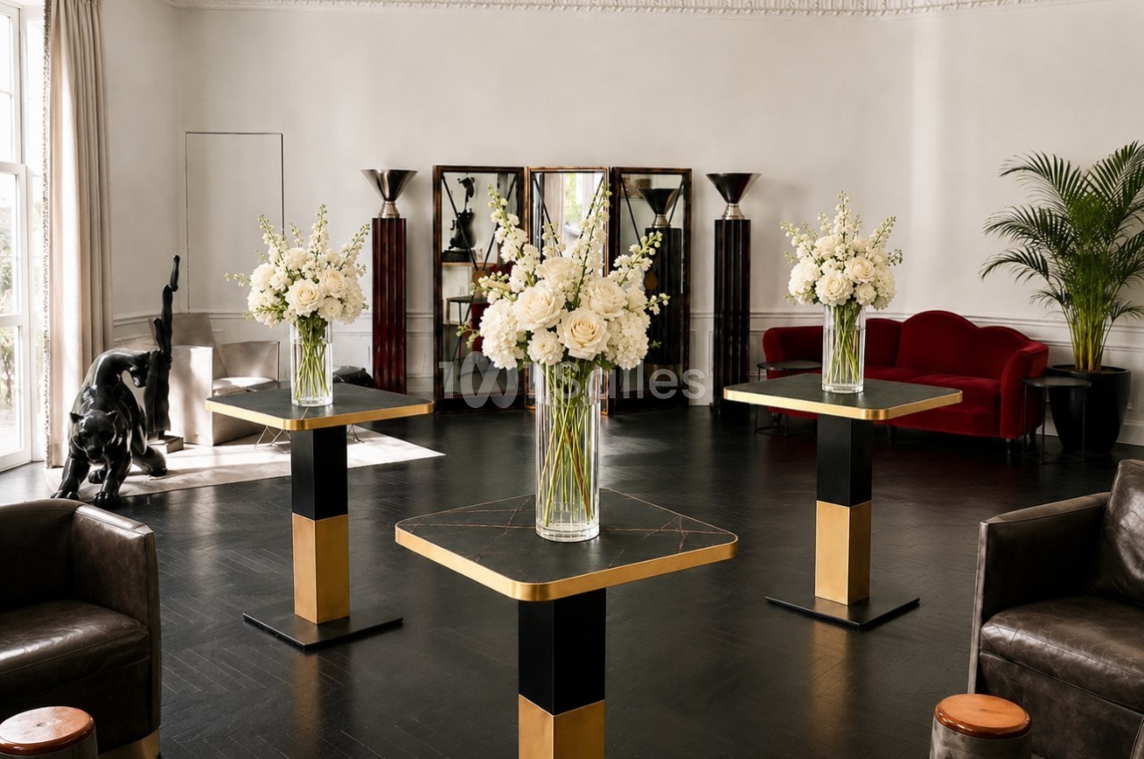 Salle élégante avec tables modernes ornées de bouquets blancs, canapé rouge, statue et plantes en arrière-plan.