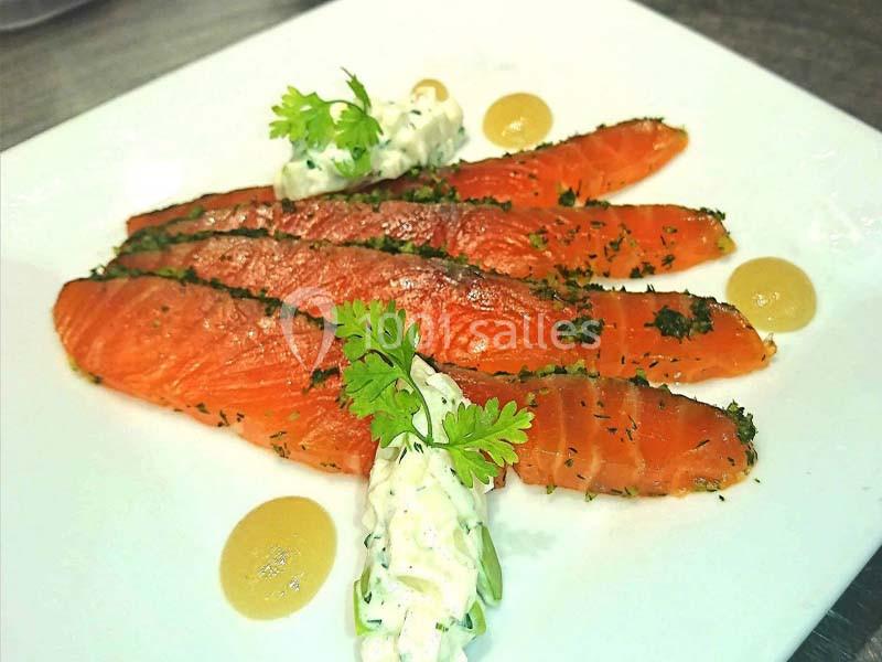 Tranches de saumon mariné garnies d'herbes, accompagnées de sauce crémeuse et de touches de condiment jaune.