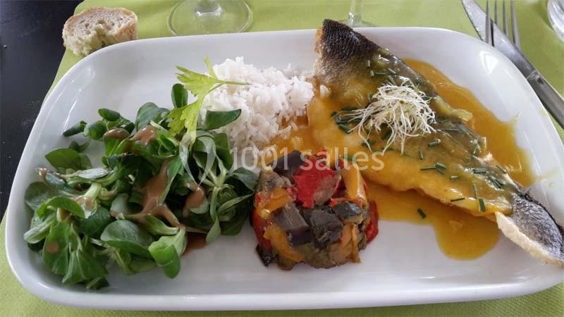 Assiette composée de poisson sauce jaune, riz, ratatouille, mâche avec vinaigrette et tranche de pain en arrière-plan.