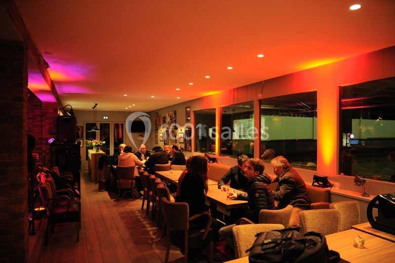 Des personnes assises autour de tables dans un restaurant à l'éclairage tamisé aux tons chauds.