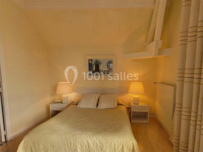Chambre lumineuse avec un lit double, deux lampes de chevet allumées et des murs peints en jaune clair.