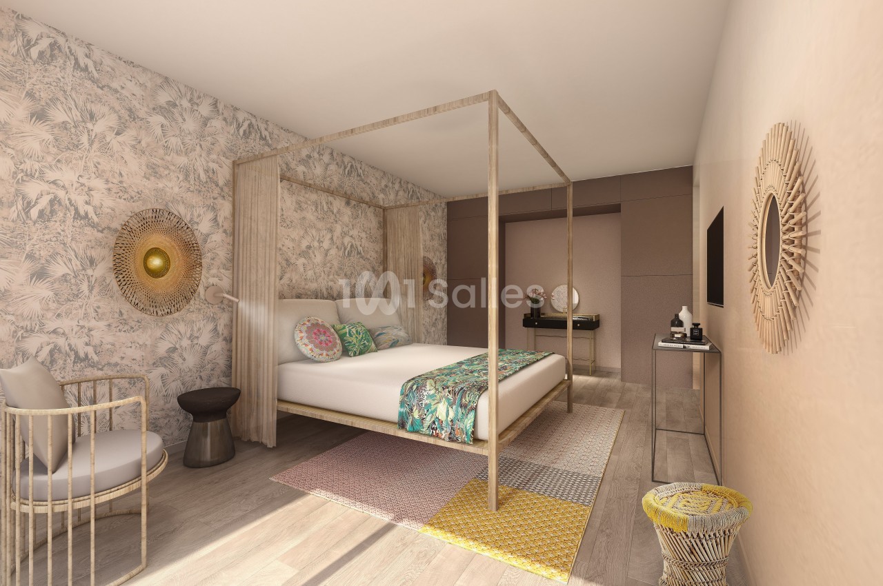 Chambre lumineuse avec lit à baldaquin, murs décorés de papier peint floral, mobilier en bois et touches colorées.