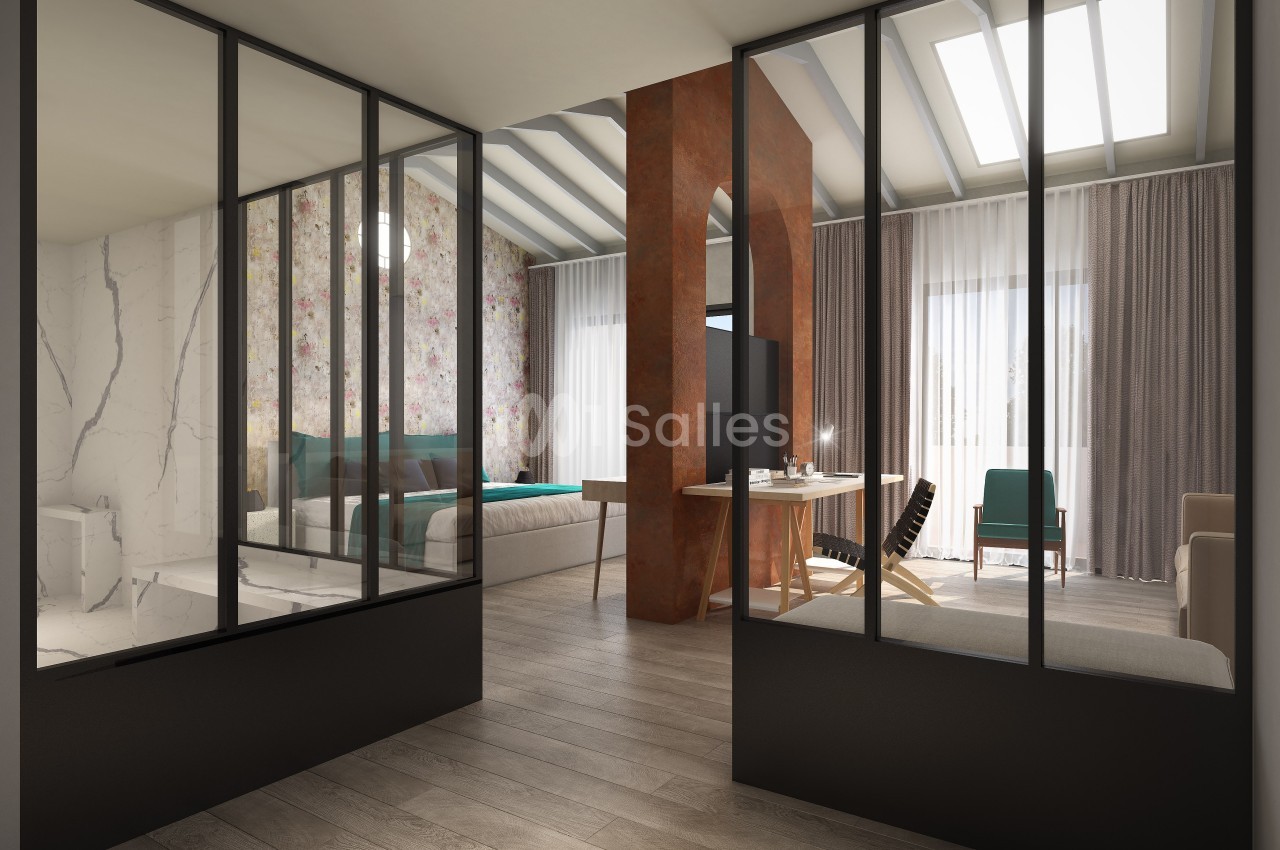 Vue intérieure d'un espace moderne avec une cloison vitrée séparant une chambre et un salon lumineux.