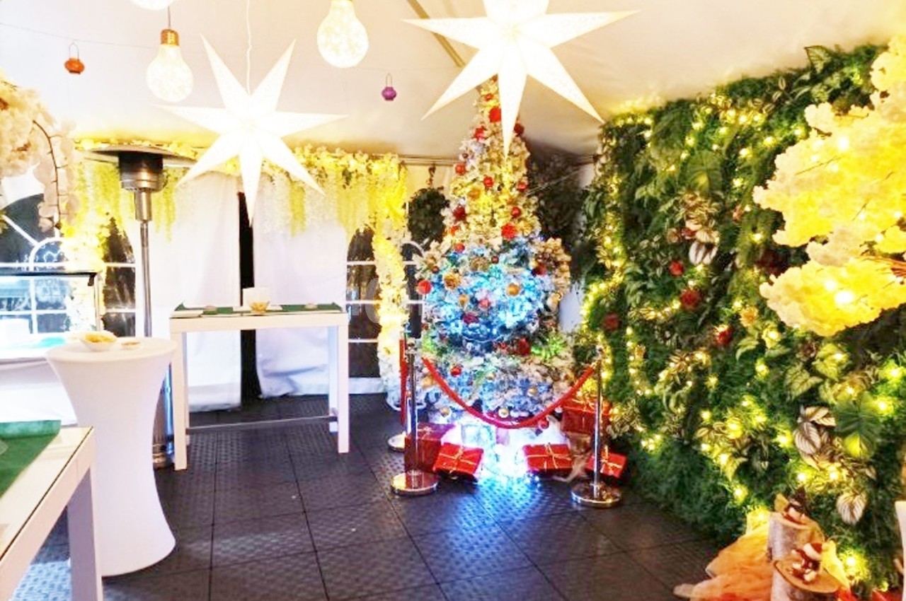 Décoration festive dans une tente illuminée avec un sapin de Noël coloré, guirlandes lumineuses et ornements.