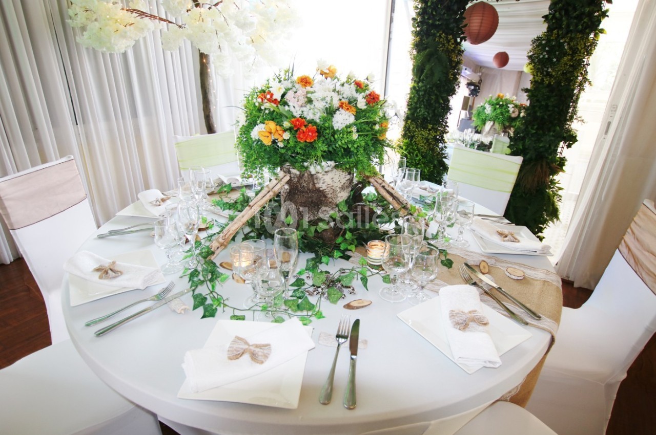 Table ronde décorée pour un événement, ornée d'un centre de table floral coloré et d'éléments naturels.