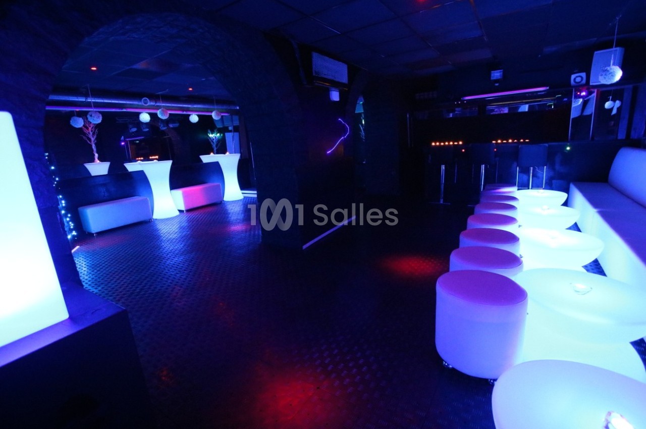 Salle de réception avec éclairage tamisé, tables lumineuses et décor moderne dans une ambiance nocturne.