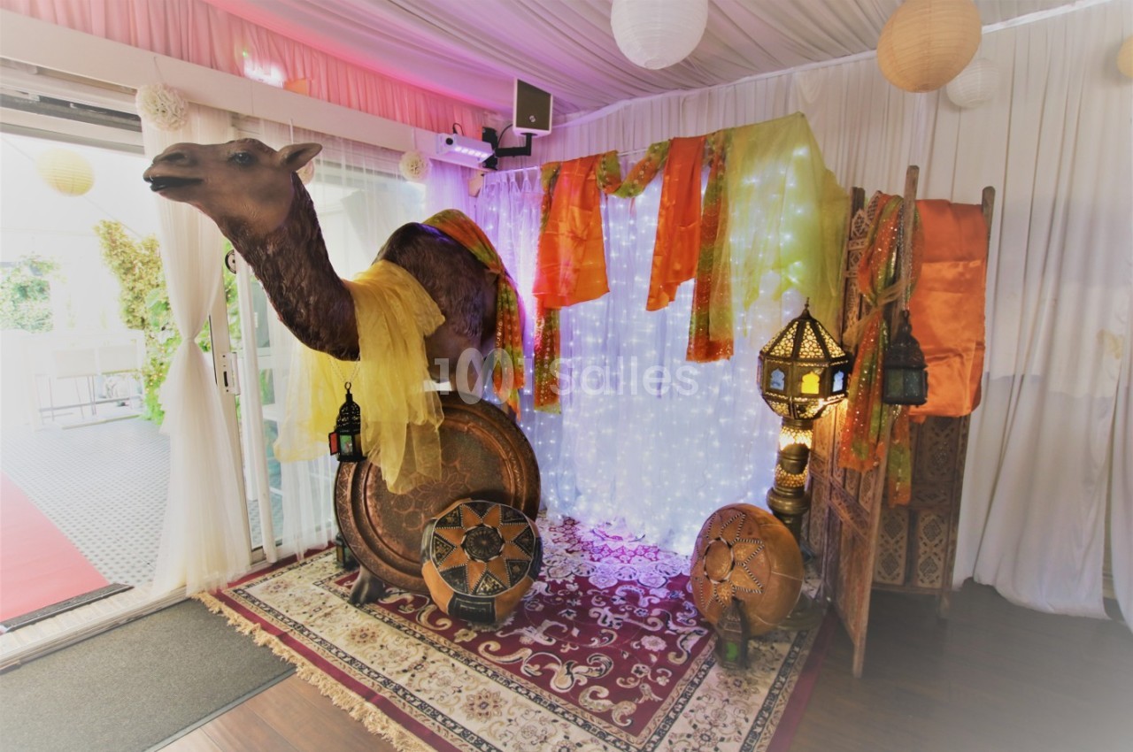 Décoration intérieure sur le thème oriental avec un faux chameau, lanternes, tapis et tissus colorés.