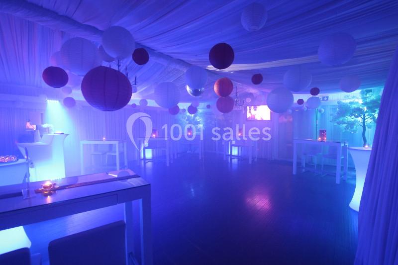 Salle décorée avec des lanternes suspendues et éclairée par une lumière tamisée bleue et violette.