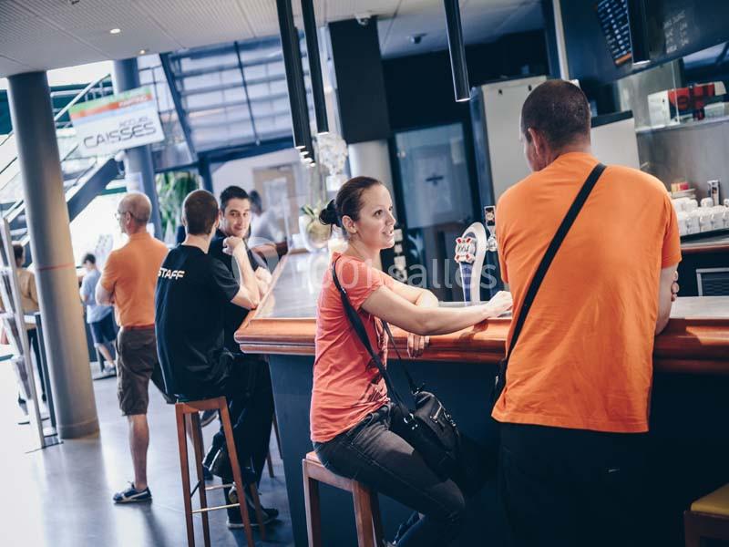 Des personnes discutent et se détendent autour d'un comptoir dans un espace lumineux avec des tables et un escalier en…