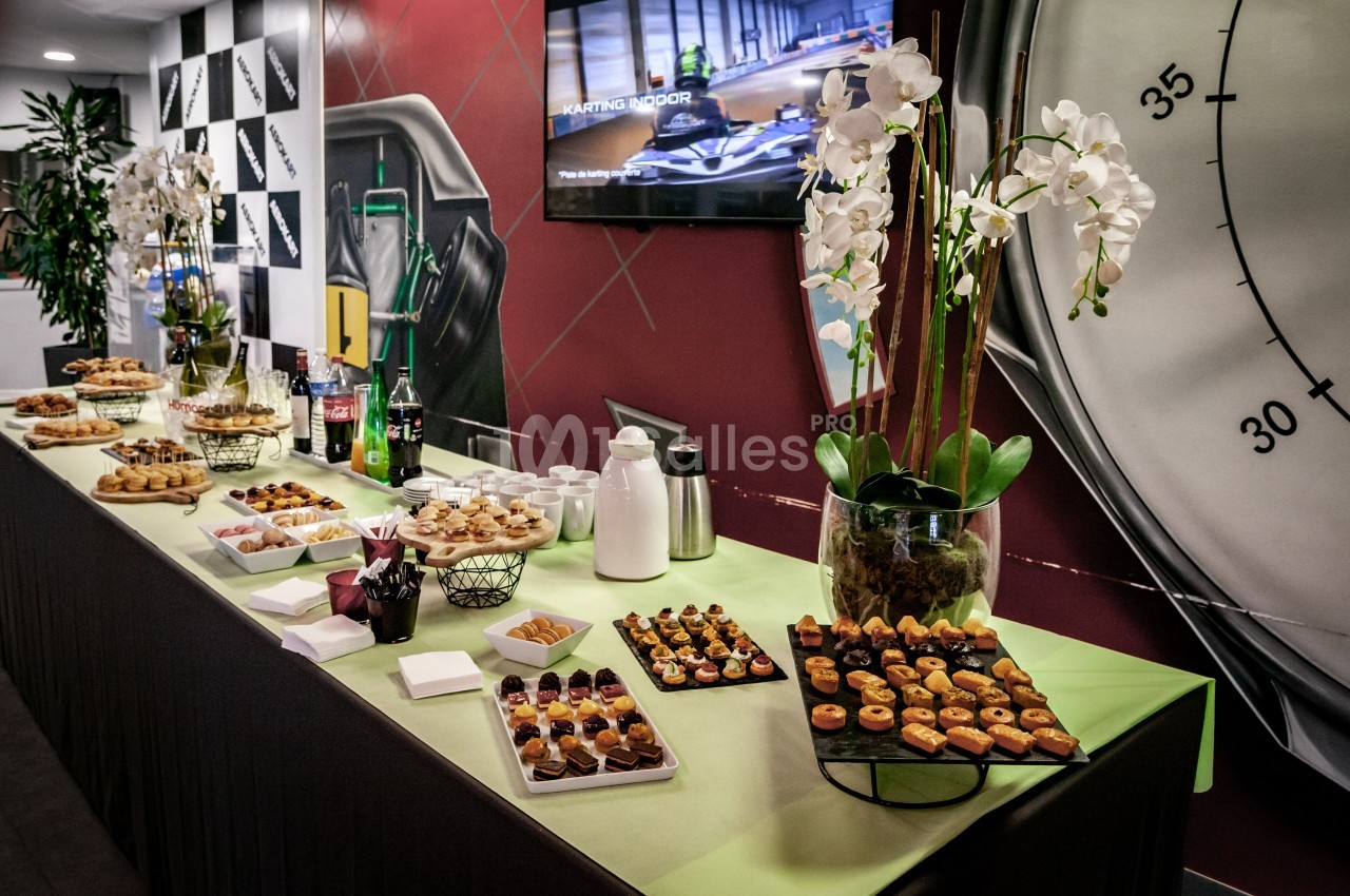 Buffet composé de petits fours, desserts, boissons et décoré avec des orchidées blanches sur une table verte.