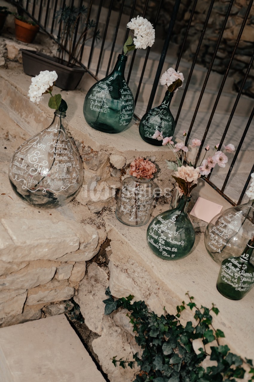 Vases en verre transparent et vert décorés de calligraphies blanches, disposés sur des marches en pierre.