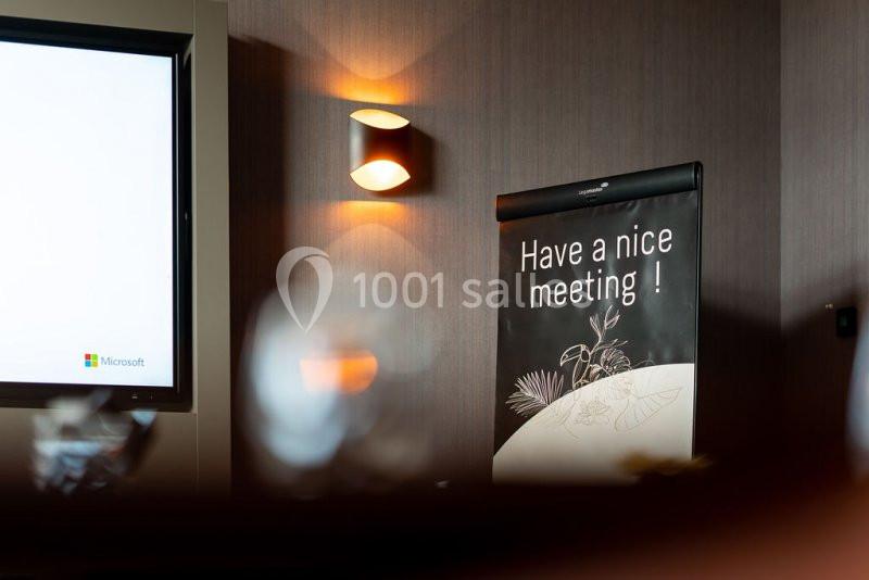Affiche avec le message ’Have a nice meeting !’ posée dans une salle de réunion faiblement éclairée.