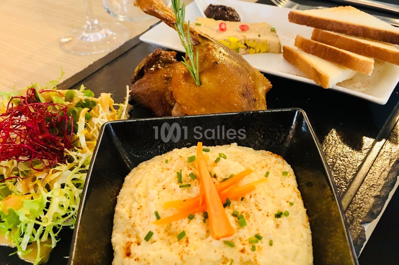 Assiette composée de confit de canard, purée garnie de carottes, salade colorée et foie gras accompagné de pain toasté.