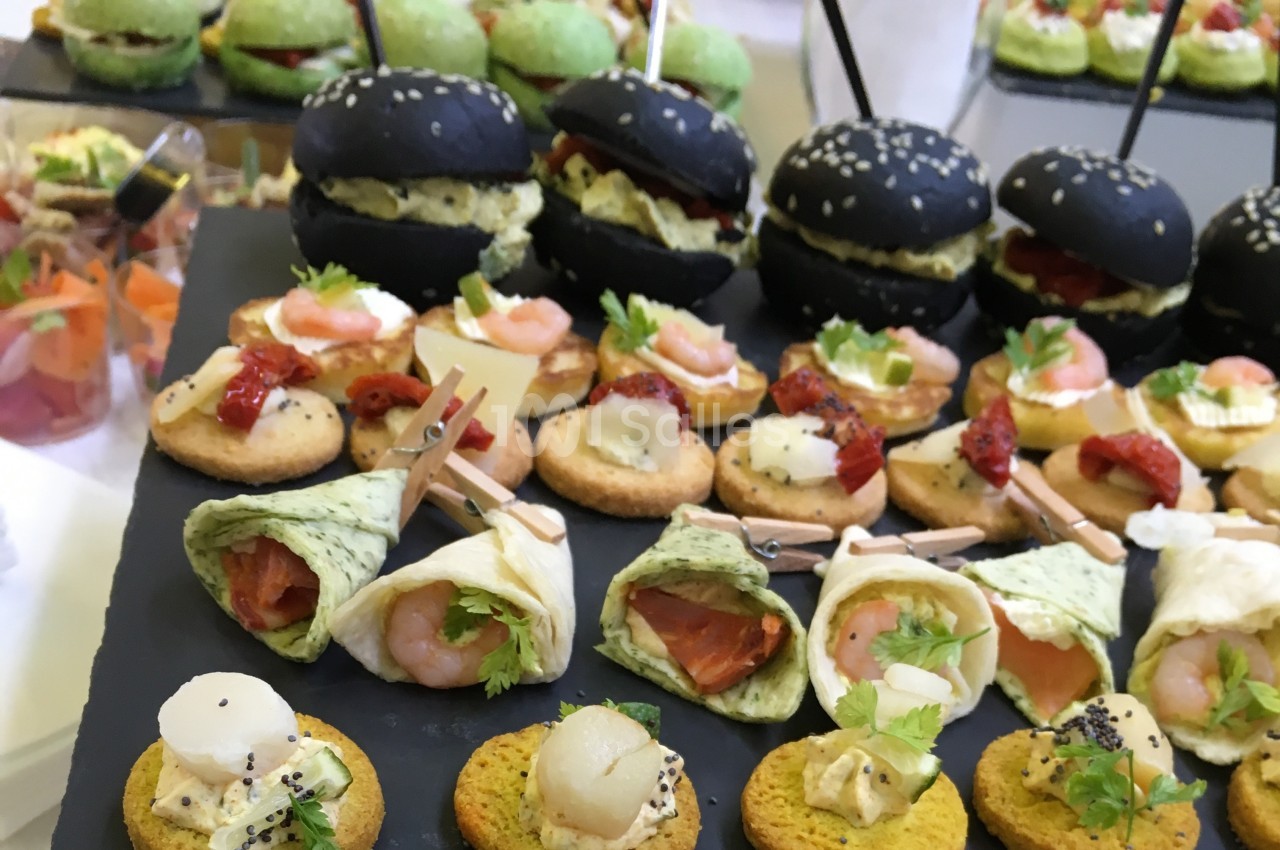 Plateau de bouchées apéritives variées comprenant mini-burgers, wraps, toasts et verrines colorées.