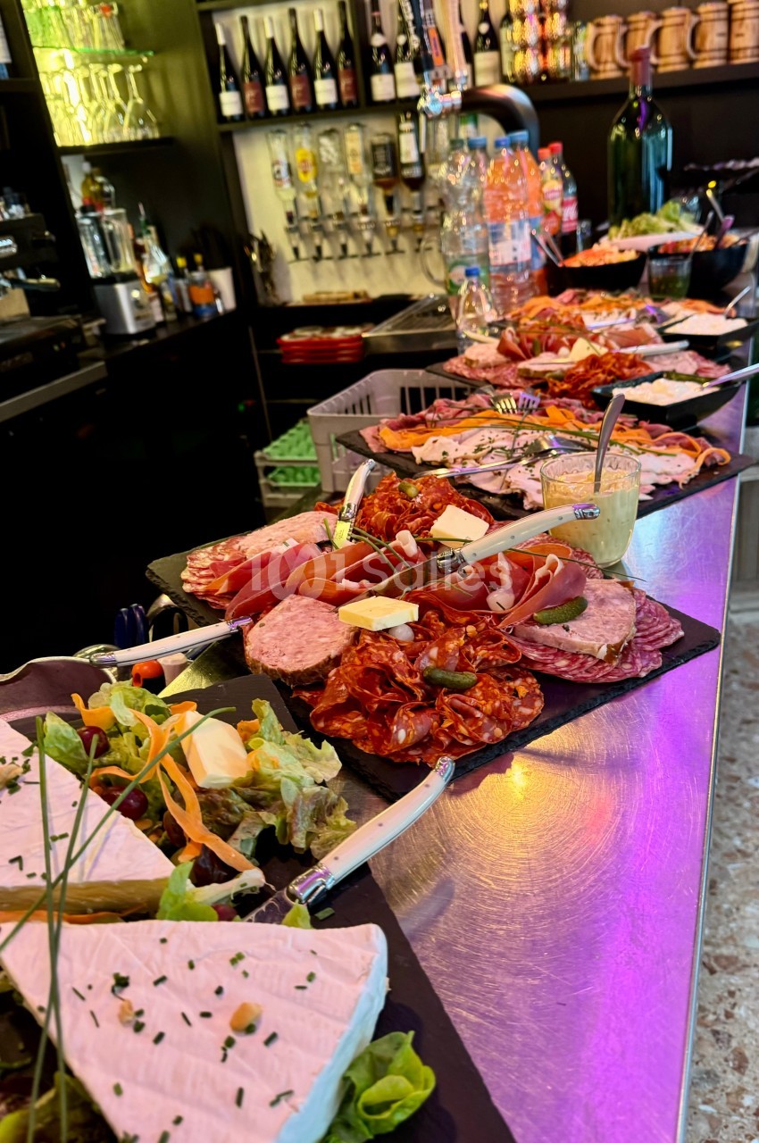 Plateau de charcuteries, fromages et accompagnements disposés sur un comptoir dans un bar ou restaurant.