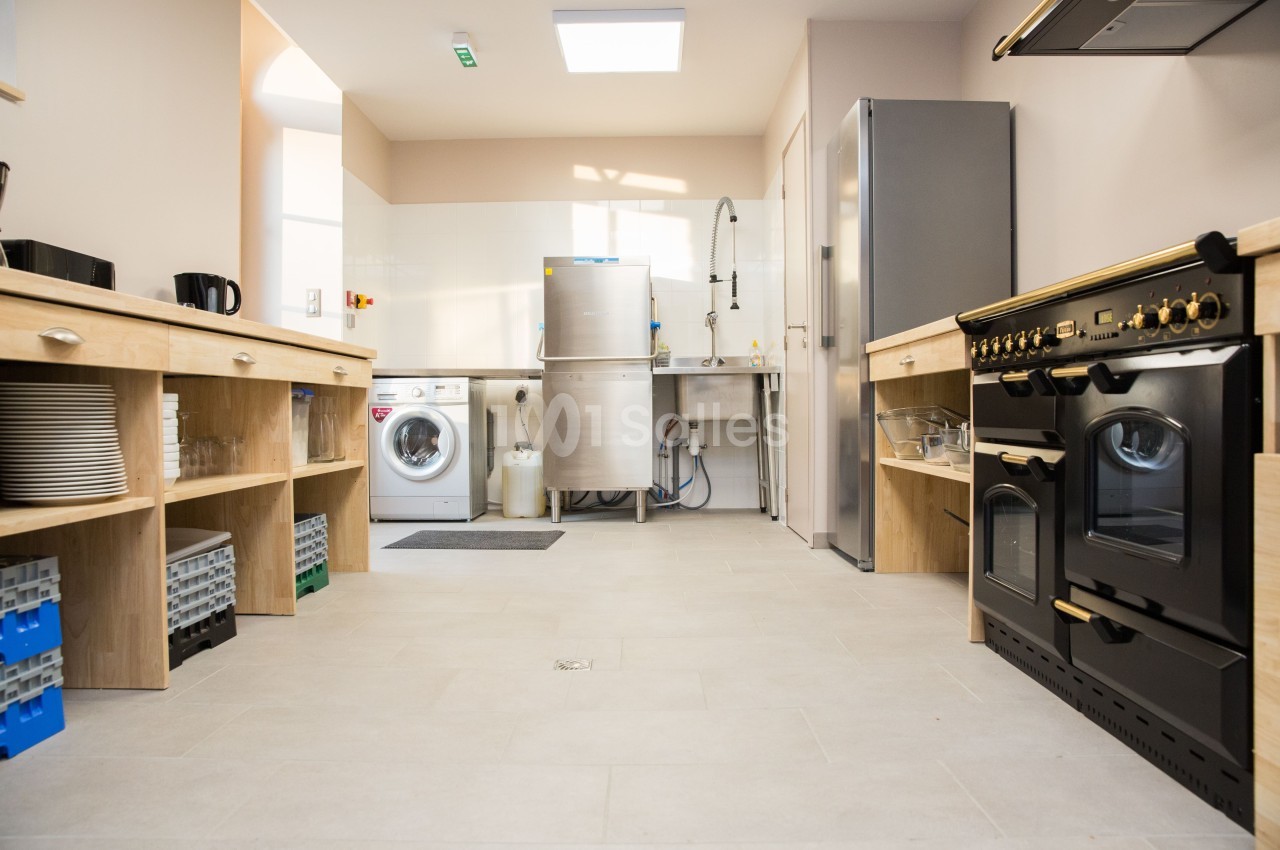 Cuisine fonctionnelle avec électroménagers modernes, plan de travail en bois, lave-linge et évier en inox.