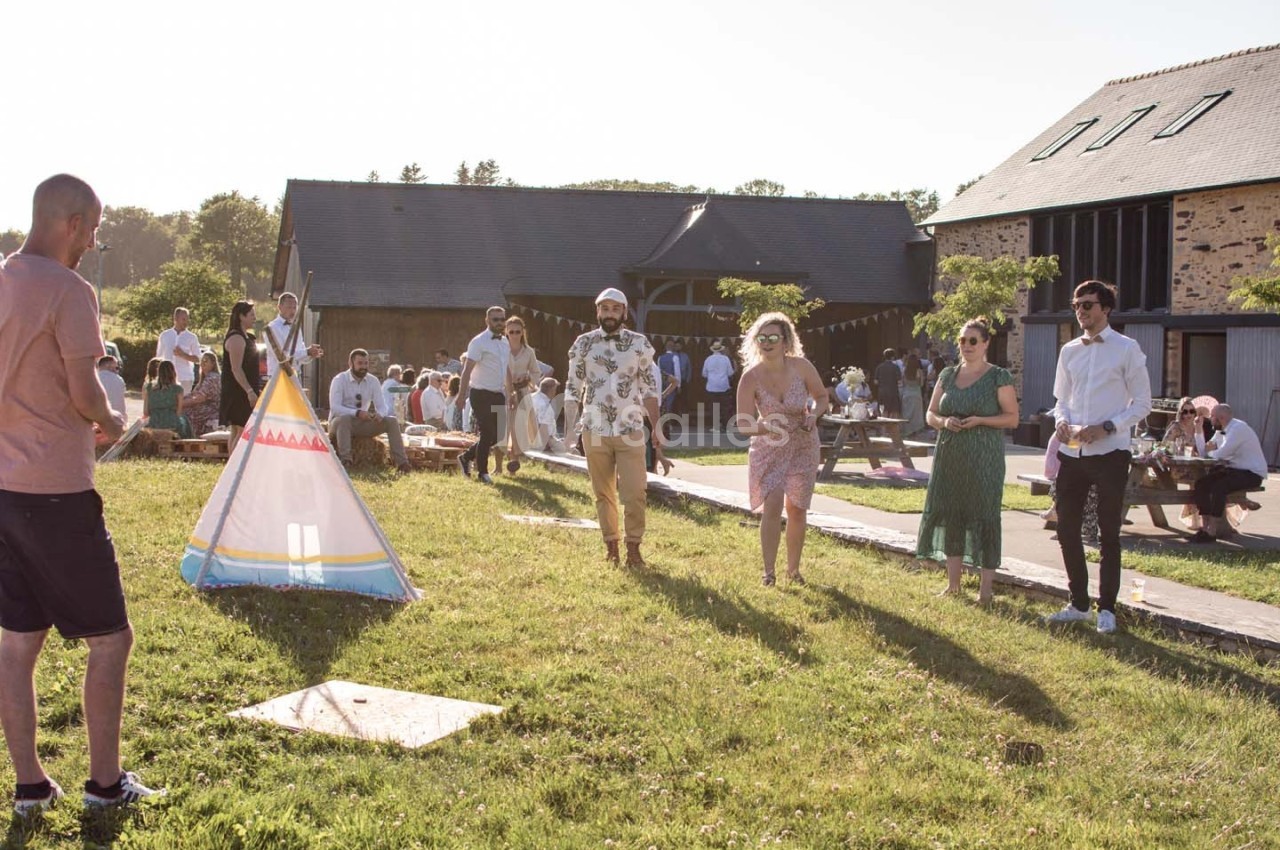 Des personnes participent à une activité en plein air près d'une tente tipi, dans un cadre champêtre et ensoleillé.