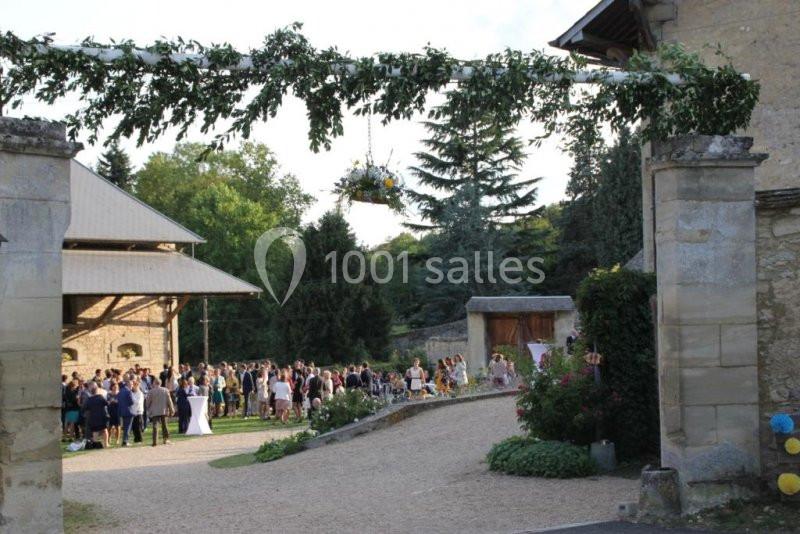 Un groupe de personnes rassemblées dans une cour extérieure décorée pour un événement festif, entourée de verdure.