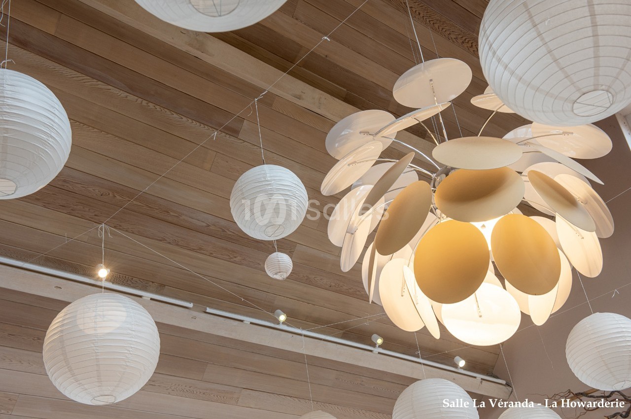 Suspension lumineuse design entourée de lanternes en papier blanc, accrochées au plafond en bois clair.