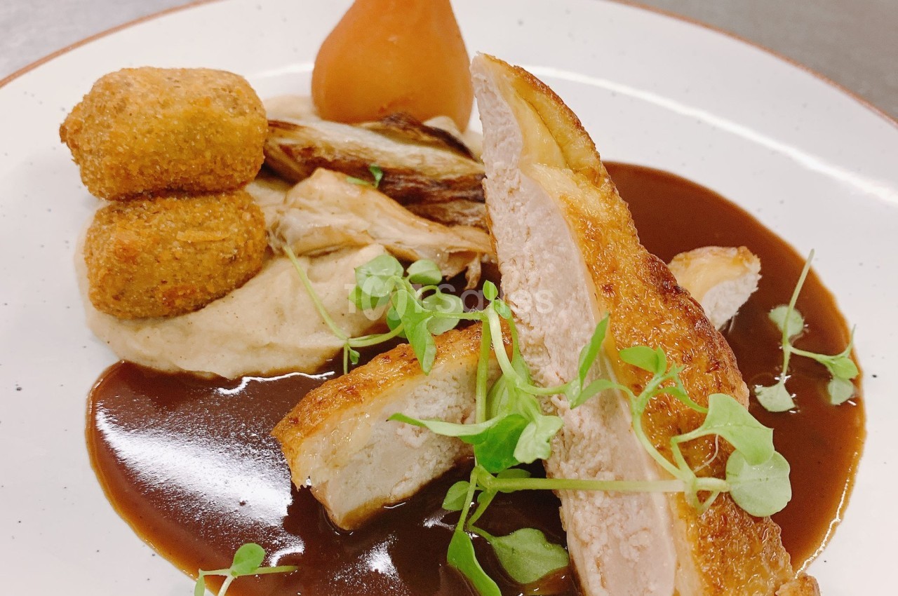 Assiette gastronomique avec suprême de volaille, croquettes, purée, poire pochée, sauce brune et jeunes pousses.